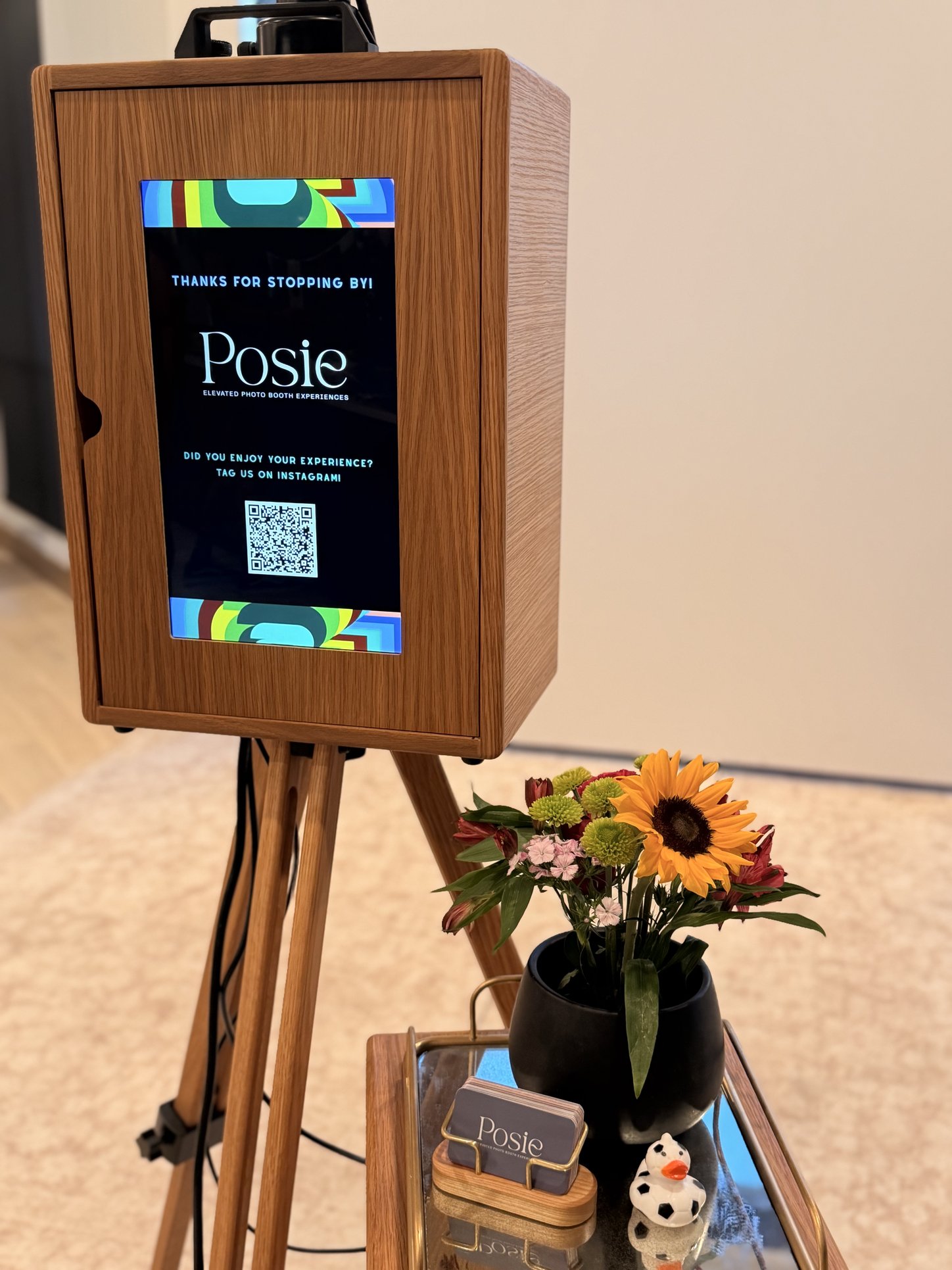 The booth with its Posie branded screen and a vase of sunflowers on the tray