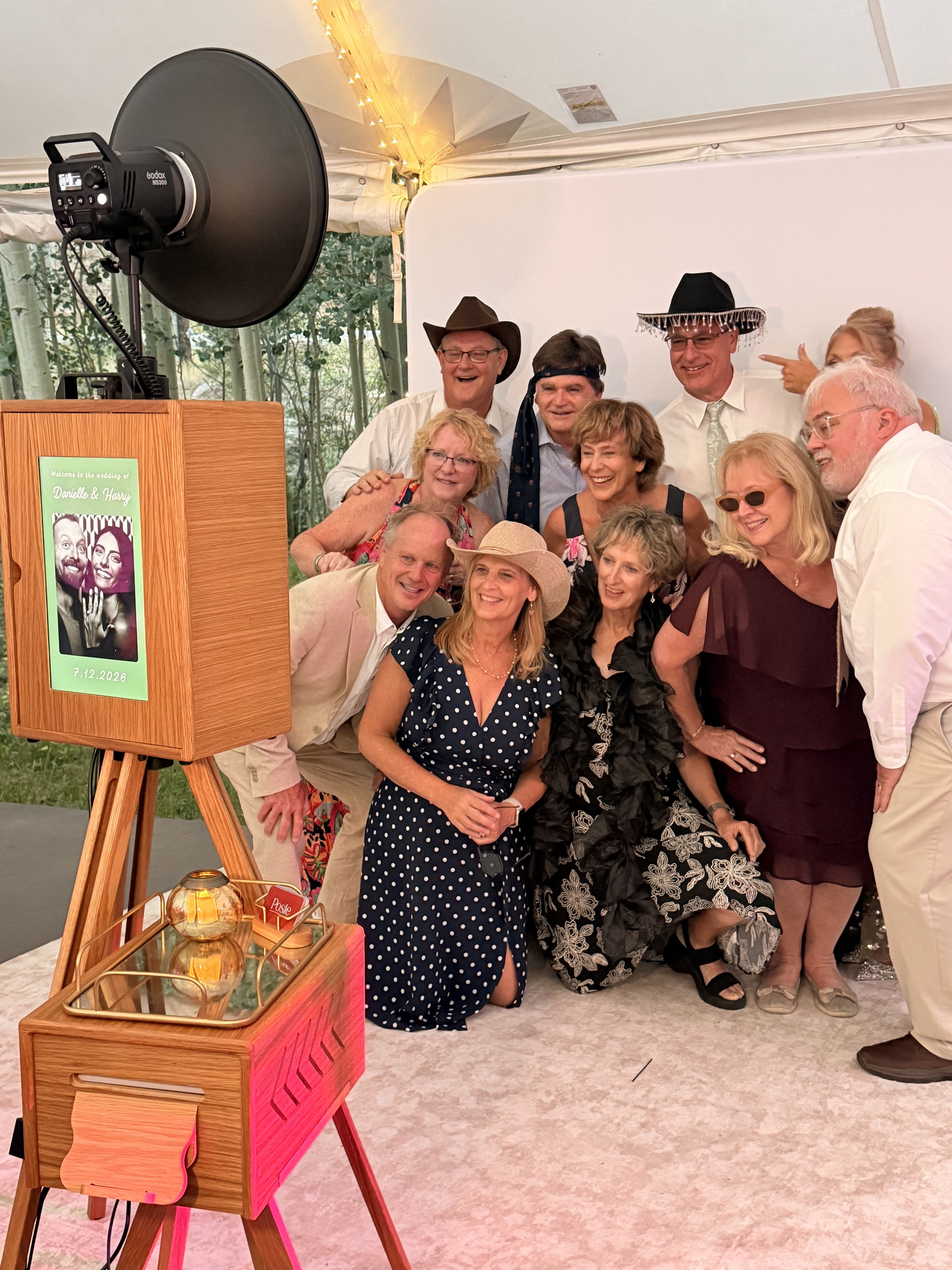 A big family group in hats posing in front of the white backdrop under a tent