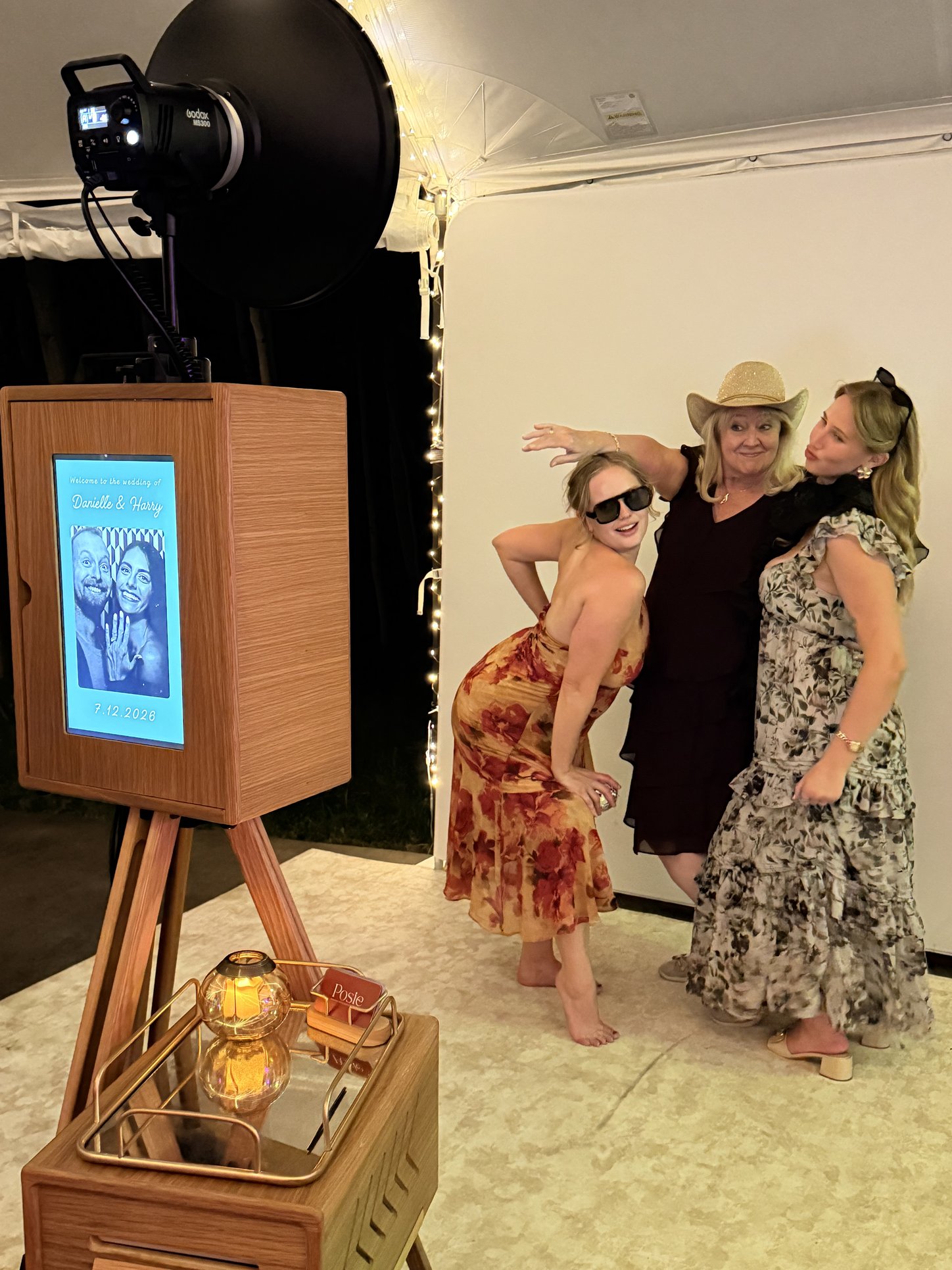 Three guests posing at the Posie booth under a tent