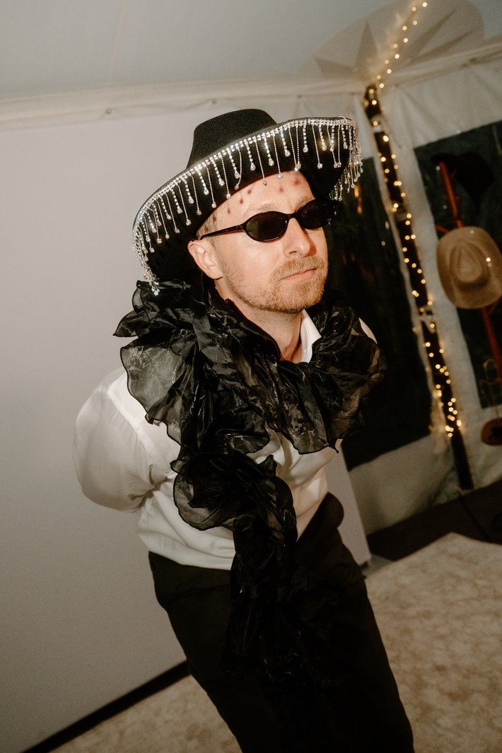 A guest in a hat and feather boa posing in the booth