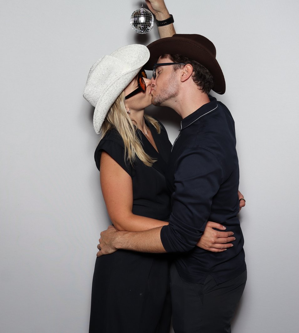 A couple in cowboy hats under a disco ball, photographed in the booth