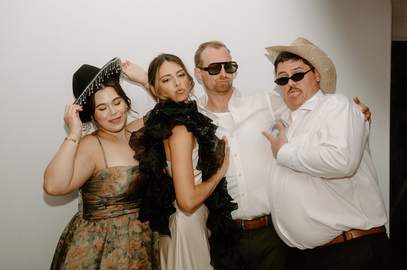 Four guests in hats and sunglasses posing for the booth