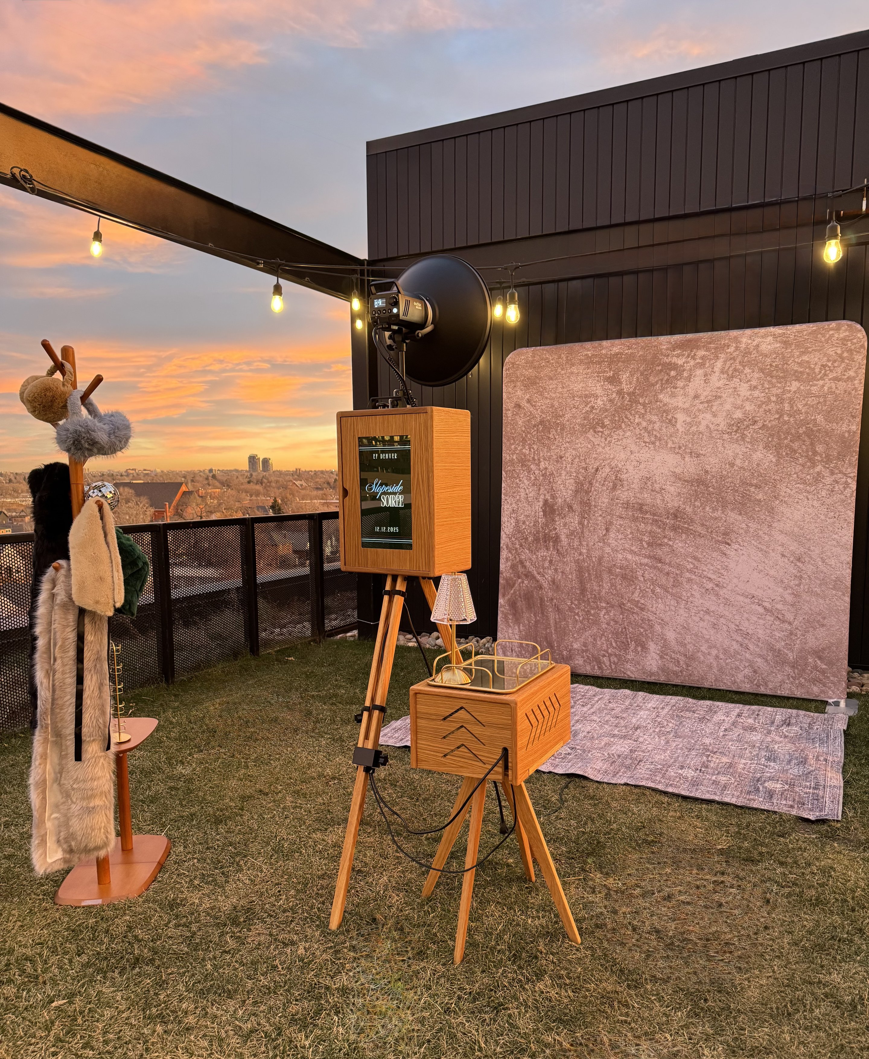 The booth set up on a rooftop at sunset with its backdrop, prop rack and drinks tray
