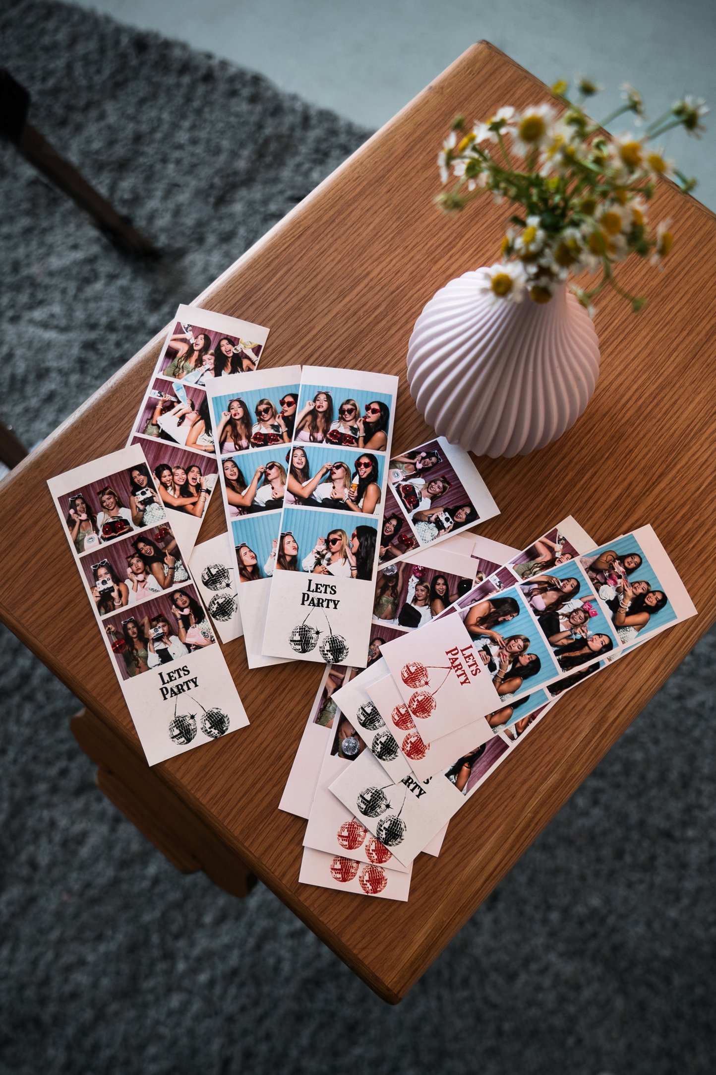 Printed photo strips laid out on a table beside flowers